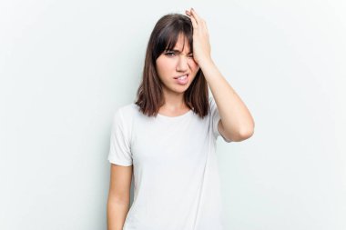 Beyaz arka planda izole edilmiş genç beyaz bir kadın bir şeyi unutuyor. Alnına avuç içi ve gözlerini kapayarak vuruyor..