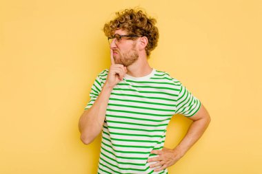 Sarı arka planda izole edilmiş genç beyaz bir adam ya sır saklıyor ya da sessizlik istiyor..