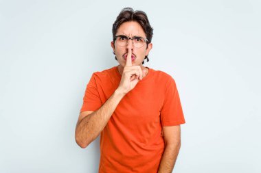 Mavi arka planda izole edilmiş genç İspanyol bir adam ya sır saklıyor ya da sessizlik istiyor..