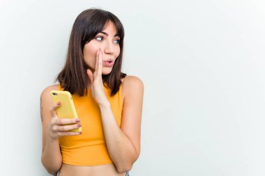 Beyaz arka planda izole edilmiş cep telefonu kullanan genç beyaz kadın gizli bir fren haberinin olduğunu söylüyor.