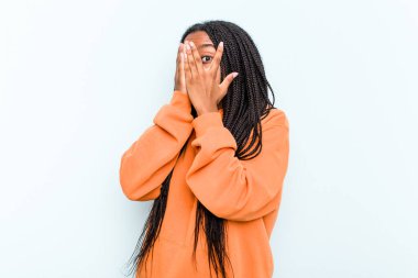 Mavi arka planda saçı olan genç Afrikalı Amerikalı kadın korkmuş ve gergin parmaklarıyla göz kırp..