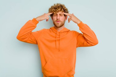 Kafkasyalı genç adam mavi arka planda izole edilmiş bir göreve odaklanmış, parmaklarını işaret ediyor..