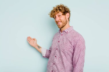 Mavi arka planda izole edilmiş beyaz bir genç hoş bir yüz ifadesi sergiliyor..