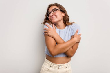 Kafkasyalı genç kadın mavi arka planda izole edilmiş, güler yüzlü ve mutlu..