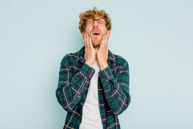 Kafkasyalı genç adam mavi arka planda izole edilmiş sızlanıyor ve ağlıyordu..