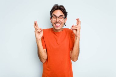 Genç İspanyol adam mavi arka planda izole edilmiş şans dilemek için şans diliyor.