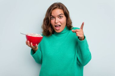 Mavi arka planda bir kase mısır gevreği tutan beyaz bir kadının bir fikri var, ilham verici bir kavram..