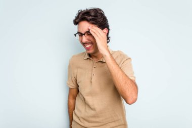 Genç İspanyol adam mavi arka planda izole edilmiş neşeli bir şekilde gülüyor. Mutluluk kavramı.