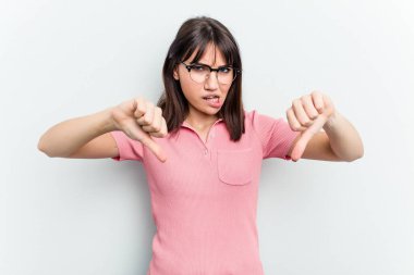 Beyaz arka planda izole edilmiş genç beyaz kadın baş parmağını aşağı gösteriyor ve hoşlanmadığını ifade ediyor..