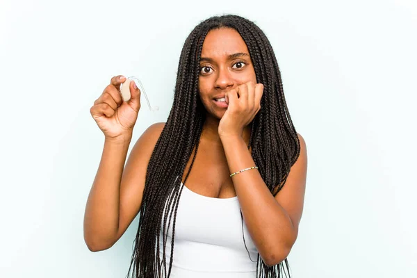 Ung Afroamerikansk Kvinna Håller Hörapparat Isolerad Blå Bakgrund Bita Naglar — Stockfoto