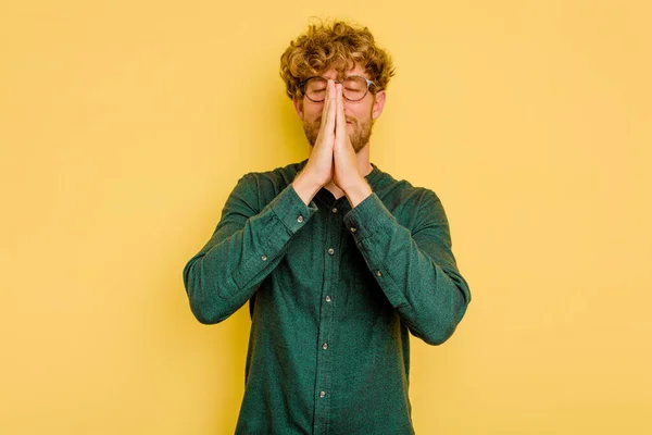 口の近くで祈りの手を保持黄色の背景に隔離された若い白人男性は 自信を感じている — ストック写真