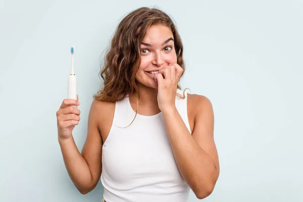 Jonge Blanke Vrouw Met Elektrische Tandenborstel Geïsoleerde Blauwe Achtergrond Bijten — Stockfoto