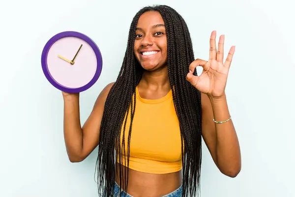 Молода Афроамериканська Жінка Тримає Годинник Ізольований Синьому Фоні Веселий Упевнений — стокове фото