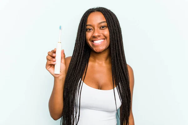 青の背景に孤立した電動歯ブラシを持っている若いアフリカ系アメリカ人女性幸せ 笑顔と陽気 — ストック写真