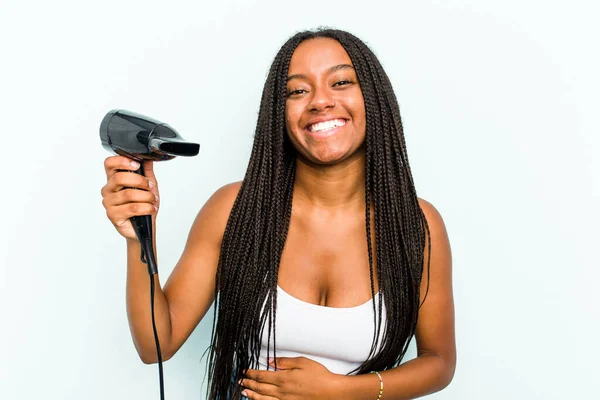 青の背景に隔離されたヘアドライヤーを持っている若いアフリカ系アメリカ人女性が笑って楽しい — ストック写真