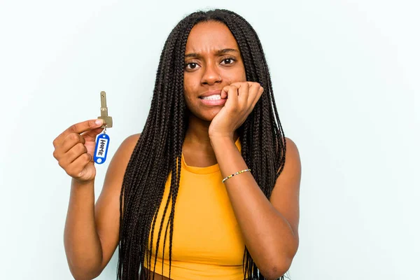 Mladá Afroameričanka Drží Domácí Klíče Izolované Modrém Pozadí Kousání Nehty — Stock fotografie
