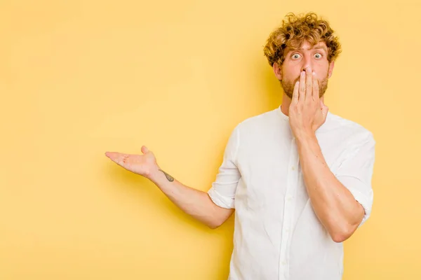 Young Caucasian Man Isolated Yellow Background Impressed Holding Copy Space — Stock Photo, Image