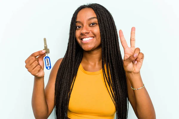Mladá Afroameričanka Drží Domácí Klíče Izolované Modrém Pozadí Ukazující Číslo — Stock fotografie