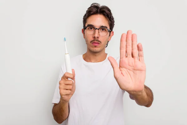 Joven Hombre Hispano Sosteniendo Cepillo Dientes Eléctrico Aislado Sobre Fondo —  Fotos de Stock