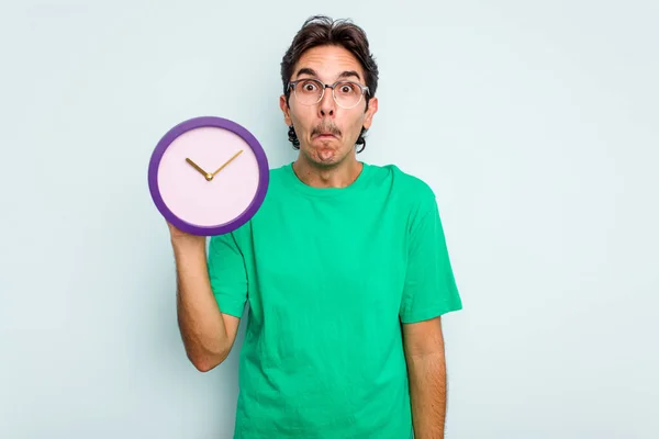 Young Hispanic Man Holding Clock Isolated White Background Shrugs Shoulders — Stock Photo, Image