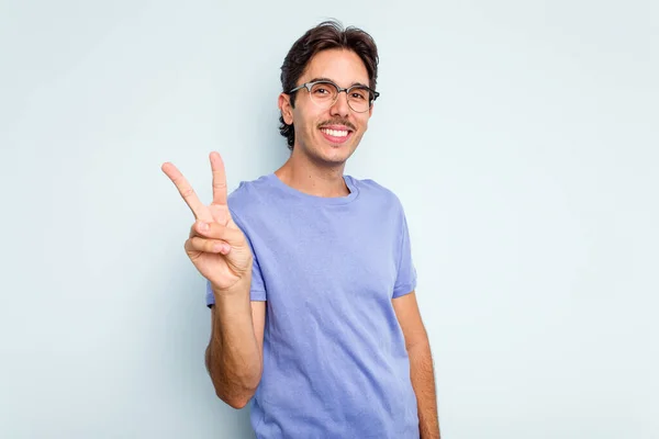 Jonge Spaanse Man Geïsoleerd Blauwe Achtergrond Met Overwinningsteken Brede Glimlach — Stockfoto