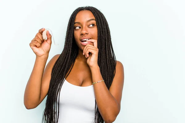 Ung Afroamerikansk Kvinna Som Håller Hörapparat Isolerad Blå Bakgrund Avslappnad — Stockfoto