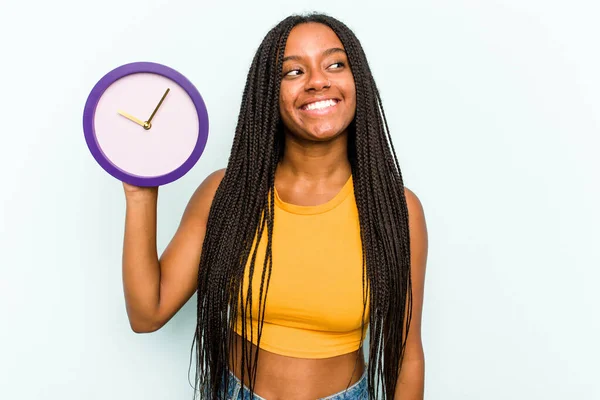 배경에 고립된 시계를 아프리카 미국인젊은 여성은 미소짓고 명랑하고 모습을 바라본다 — 스톡 사진