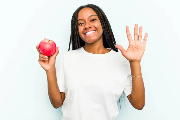 Ung Afroamerikansk Kvinna Håller Ett Äpple Isolerat Blå Bakgrund Ler — Stockfoto