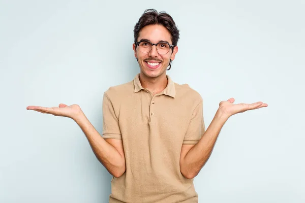 Young Hispanic Man Isolated Blue Background Makes Scale Arms Feels — ストック写真