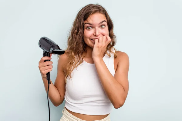 Young Caucasian Woman Holding Hairdryer Isolated Blue Background Biting Fingernails — Stock Photo, Image