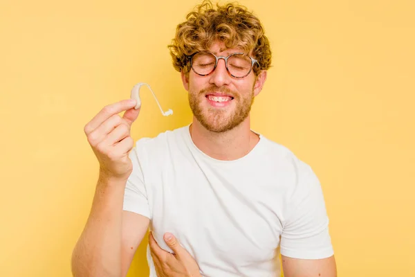 Young Caucasian Man Wearing Hearing Aid Isolated Yellow Background Laughing — Stock Photo, Image