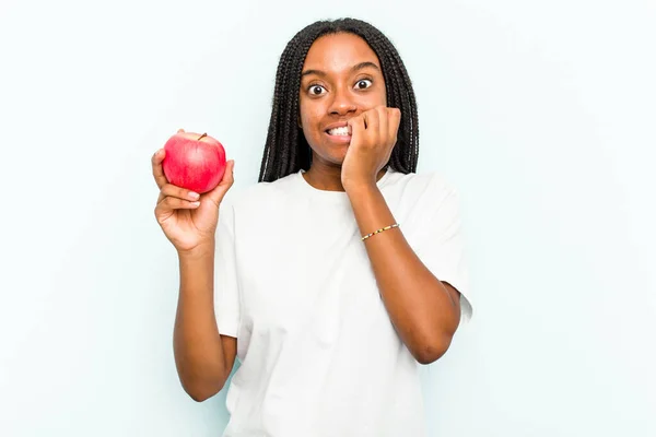 Ung Afroamerikansk Kvinna Håller Ett Äpple Isolerad Blå Bakgrund Bita — Stockfoto