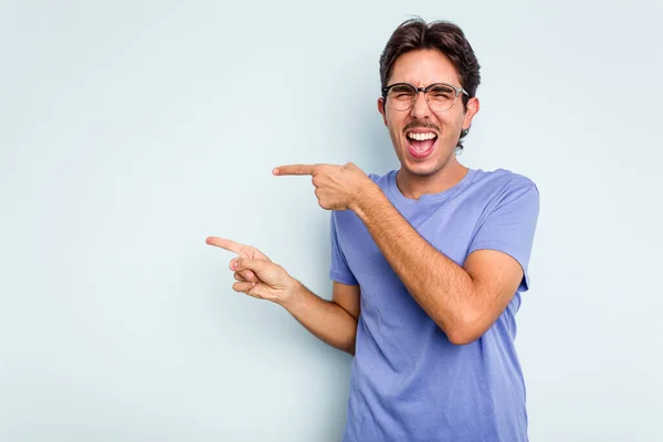 Young Hispanic Man Isolated Blue Background Excited Pointing Forefingers Away — стоковое фото