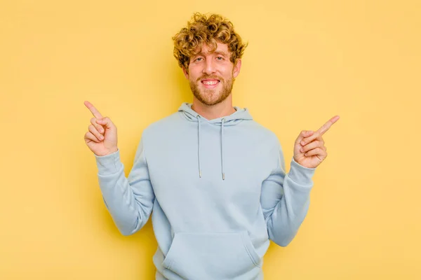 Young Caucasian Man Isolated Yellow Background Pointing Different Copy Spaces — Stock Photo, Image