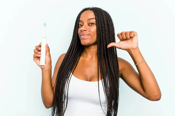青の背景に隔離された電動歯ブラシを持っている若いアフリカ系アメリカ人女性は誇りと自信を感じています 次の例に従うこと — ストック写真