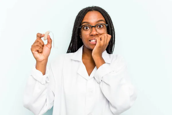 Ung Afroamerikansk Otorhinolaryngolog Kvinna Som Håller Hörapparat Isolerad Blå Bakgrund — Stockfoto