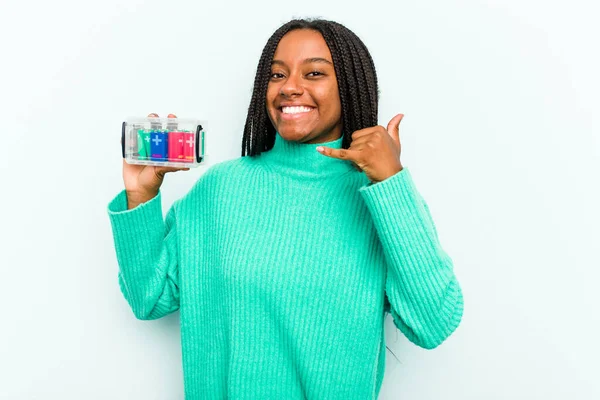 年轻的非洲裔美国妇女手持一个蓝色背景的电池盒 用手指表示一个手机呼叫手势 — 图库照片