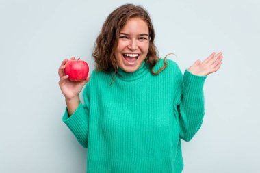 Mavi arka planda soyutlanmış beyaz bir kadın hoş bir sürprizle karşılaşıyor, heyecanlı ve el kaldırıyor..