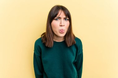 Sarı arka planda izole edilmiş beyaz bir kadın. Komik ve dost canlısı bir dil uzatıyor..
