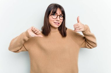 Beyaz arka planda izole edilmiş genç beyaz bir kadın baş parmağını kaldırıyor ve baş parmağını aşağı gösteriyor, zor seçim konsepti.