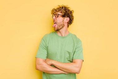 Sarı arka planda izole edilmiş beyaz bir genç. Komik ve dost canlısı bir dil uzatıyor..