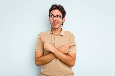 Mavi arka plan noktalarında izole edilmiş genç İspanyol adam iki seçenek arasında seçim yapmaya çalışıyor..