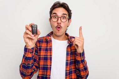 Beyaz arka planda izole edilmiş araba anahtarlarını tutan İspanyol genç adamın harika bir fikri var, yaratıcılık kavramı..