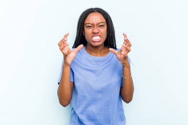 Mavi arka planda saçları olan genç Afrikalı Amerikalı kadın gergin elleriyle çığlık atıyor..