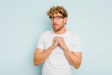 Kafkasyalı genç adam mavi arka planda izole edilmiş korkmuş ve korkmuş..