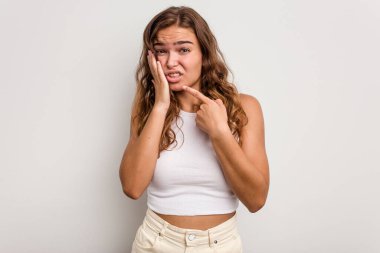 Mavi arka planda izole genç beyaz kadın güçlü bir diş ağrısı, azıdişi ağrısı var..