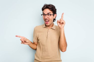 Mavi arka planda izole edilmiş genç İspanyol adam farklı kopya alanlarını gösteriyor, birini seçiyor, parmaklarıyla gösteriyor..