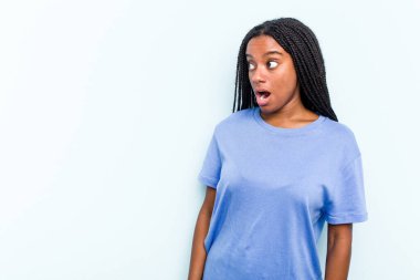 Mavi arka planda saç örgüsü olan genç Afrikalı Amerikalı kadın gördüğü bir şey yüzünden şoka uğruyor..