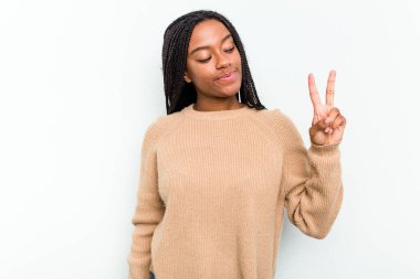 Beyaz arka planda izole edilmiş genç Afrikalı Amerikalı kadın neşeli ve kaygısız parmaklarıyla barış sembolü gösteriyor..