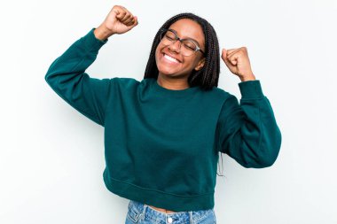 Beyaz arka planda izole edilmiş genç bir Afrikalı Amerikalı kadın özel bir günü kutluyor, atlıyor ve enerjiyle kollarını kaldırıyor..
